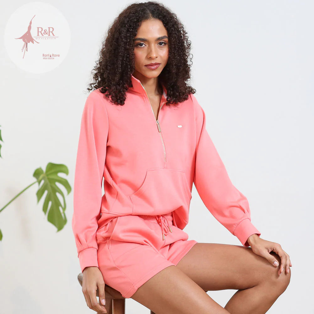 Woman wearing a pink tracksuit with a white background and R&R brand logo.