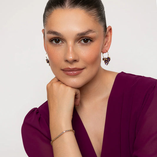 Woman wearing a purple dress with jewelry on a plain background