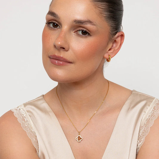 Woman wearing a gold necklace and earrings on a plain background
