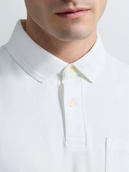 Close-up of a man wearing a white polo shirt, showing the collar, button placket, and part of the chest pocket against a light gray background.