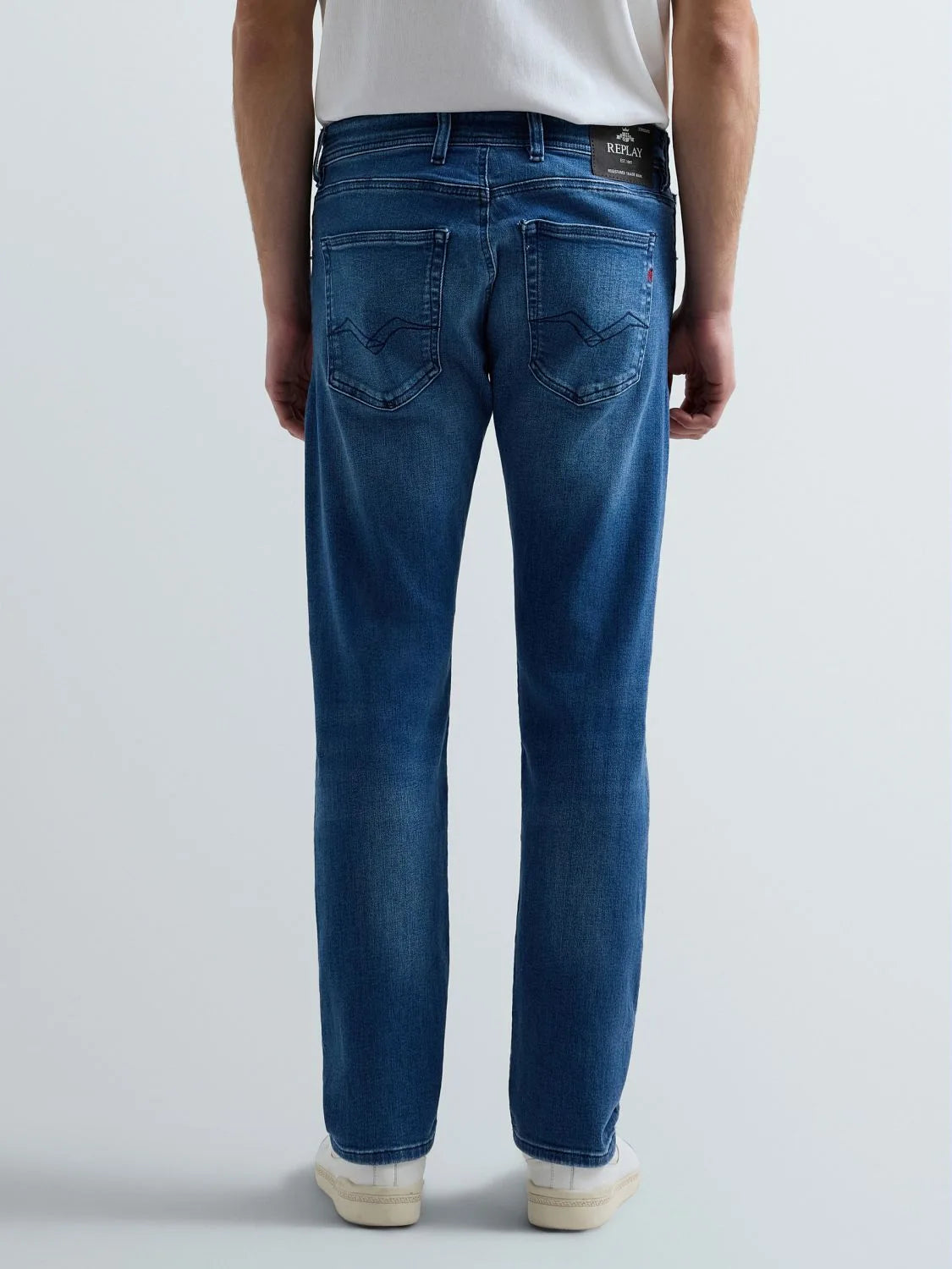 Person wearing blue jeans on a light gray background