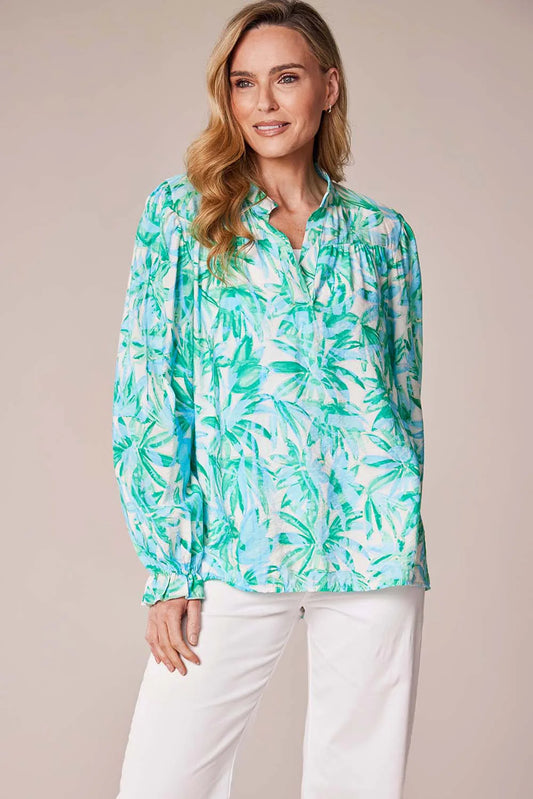 Woman wearing a green and white leaf-patterned blouse against a beige background