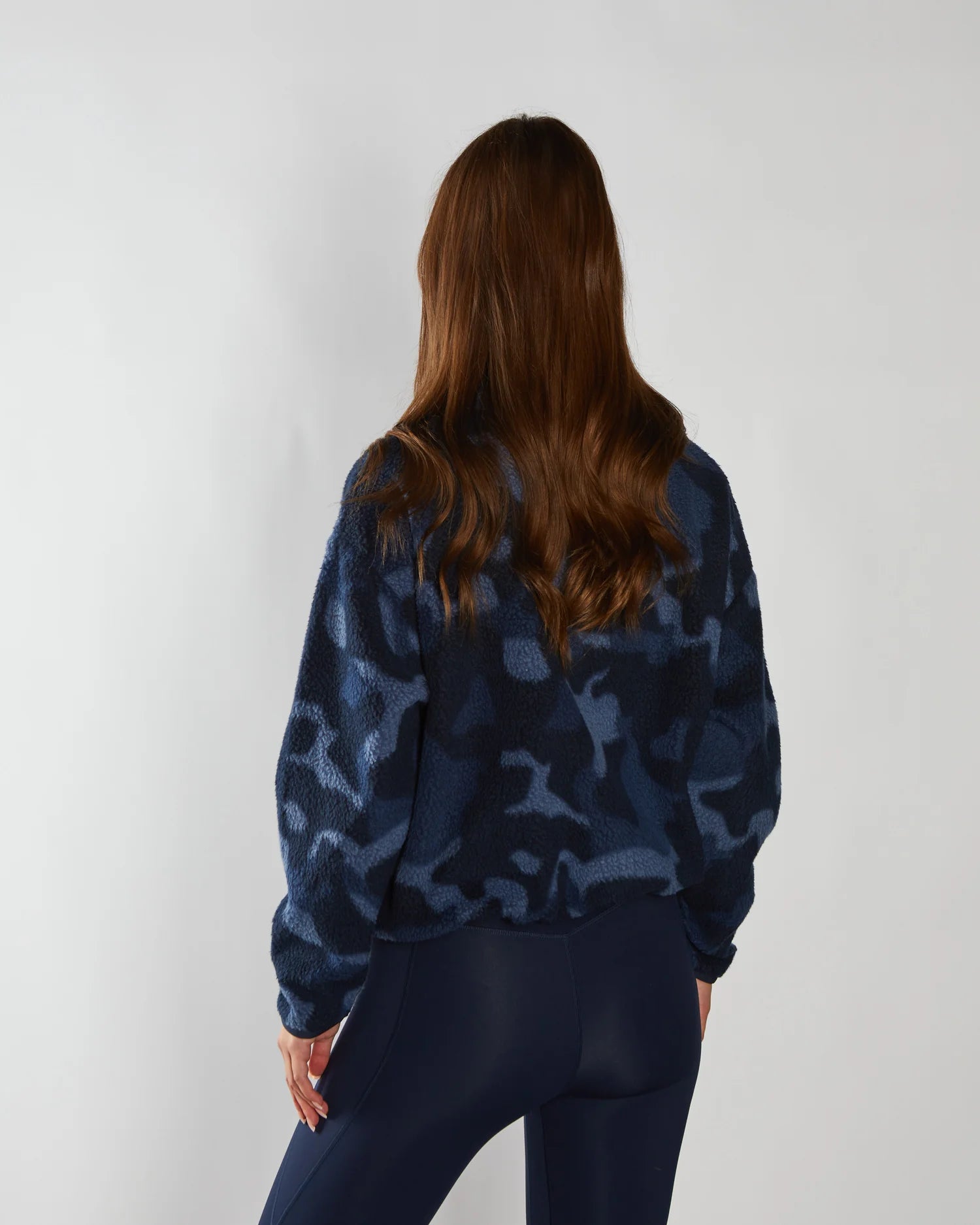 Person wearing a blue camouflage sweater and pants on a white background