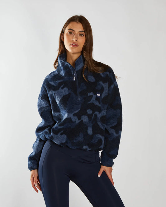 Woman wearing a blue camouflage sweater against a white background