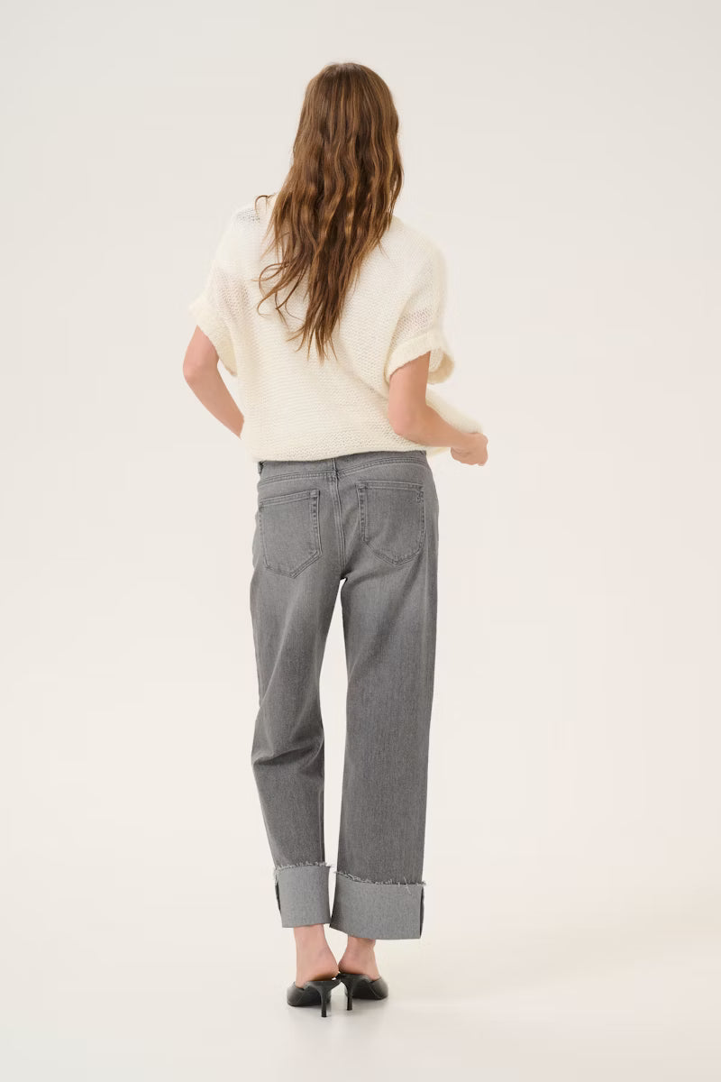 Person wearing a white shirt and gray pants on a plain background