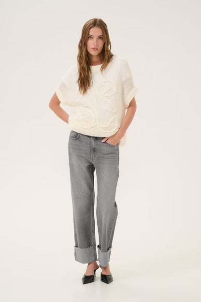 Woman wearing a white sweater and gray jeans on a white background