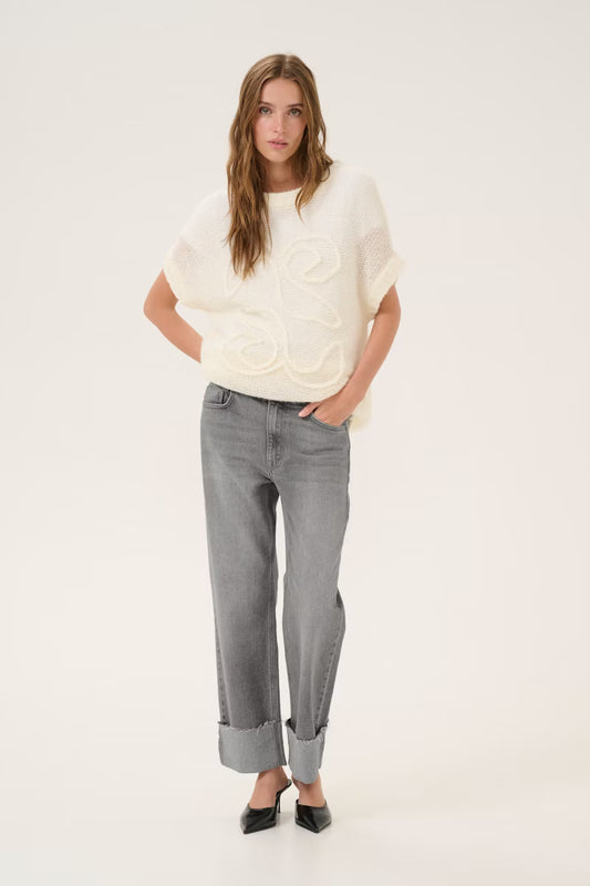 Woman wearing a white sweater and gray jeans on a white background