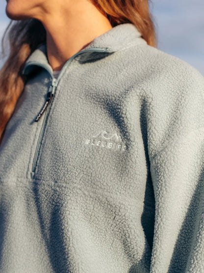 Close-up of a person wearing a gray fleece jacket with a brand logo on the chest.