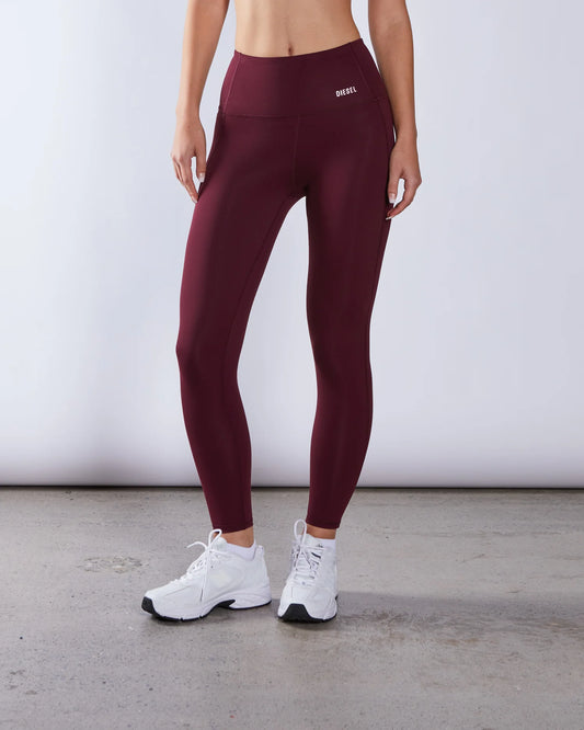 Person wearing maroon leggings with a visible brand logo on a light gray background