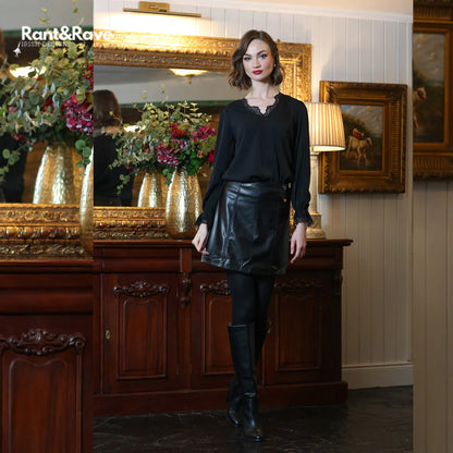 Woman in black outfit standing in a room with decorative elements and 'Rant&Raw' branding.