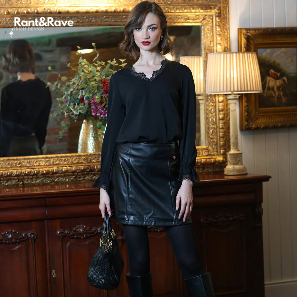 Woman in black outfit standing in a room with decorative elements and 'Rant&Rave' branding.