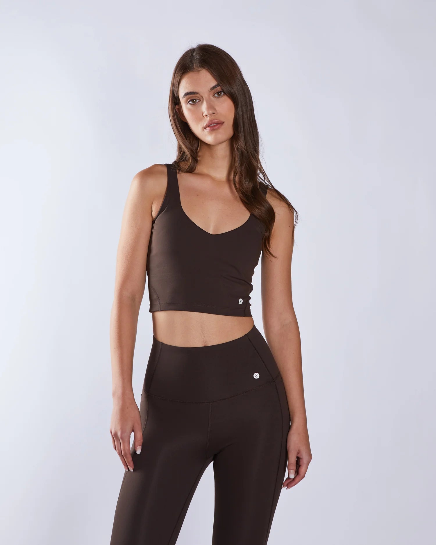 Woman wearing a brown sports bra and leggings on a white background