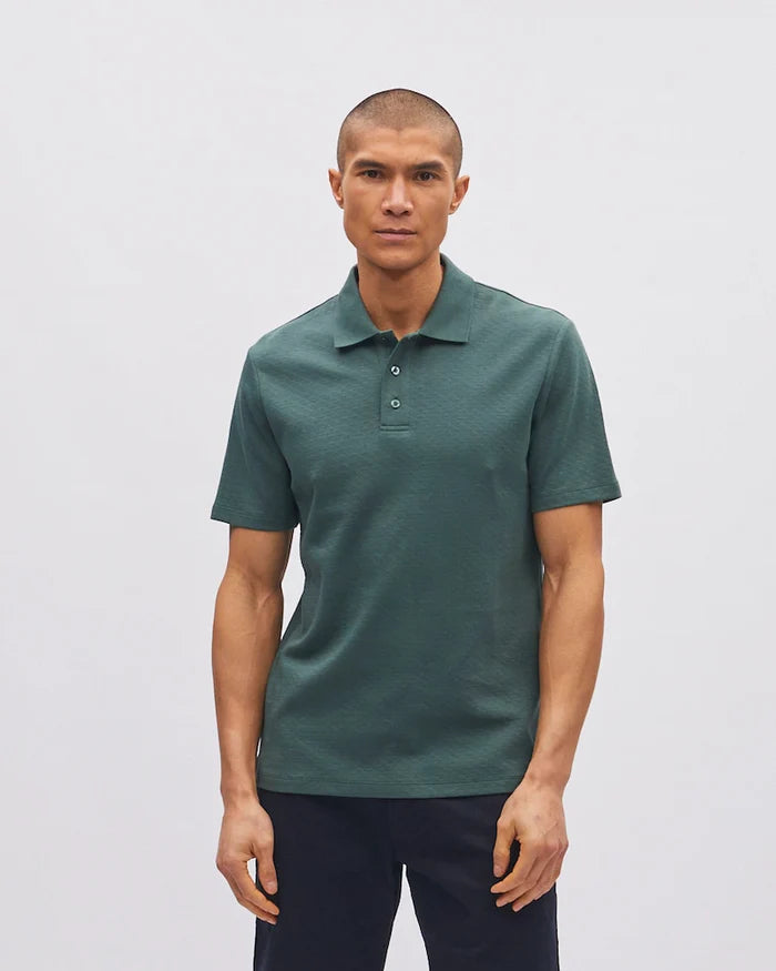 Man wearing a green polo shirt against a plain background
