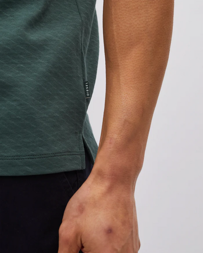 Close-up of a person wearing a green t-shirt with a brand logo on a light gray background