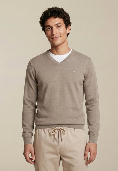 Man wearing a beige sweater and pants on a plain background
