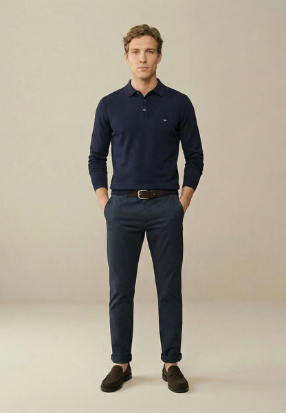 Man wearing a navy blue polo shirt and pants against a beige background