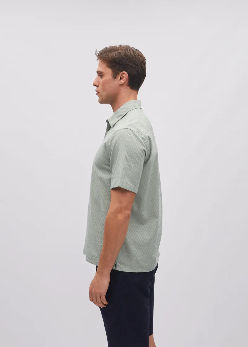 Man wearing a green patterned shirt on a light gray background