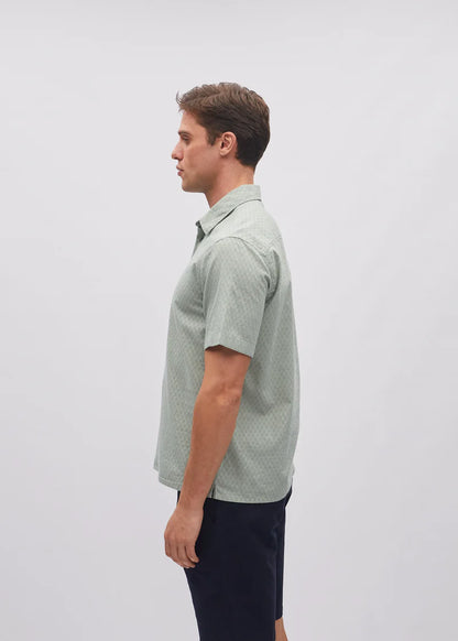 Man wearing a green patterned shirt on a light gray background