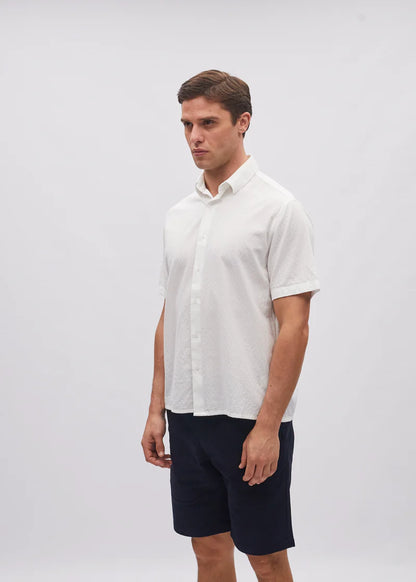 Man wearing a white shirt and navy shorts on a plain background