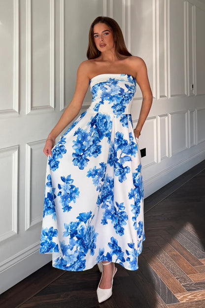 Woman wearing a strapless blue floral dress in a room with white paneled walls.