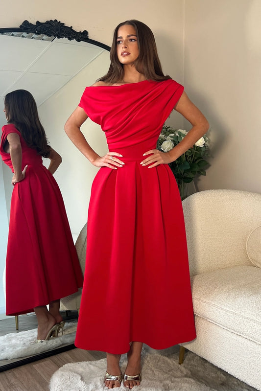 Woman wearing a red off-shoulder dress standing in front of a mirror.