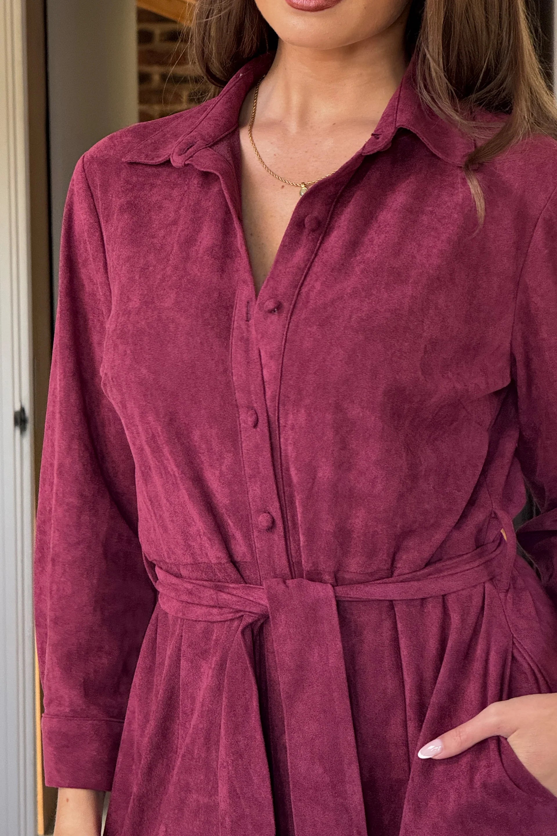 Close-up of a person wearing a burgundy velvet dress with a belt.