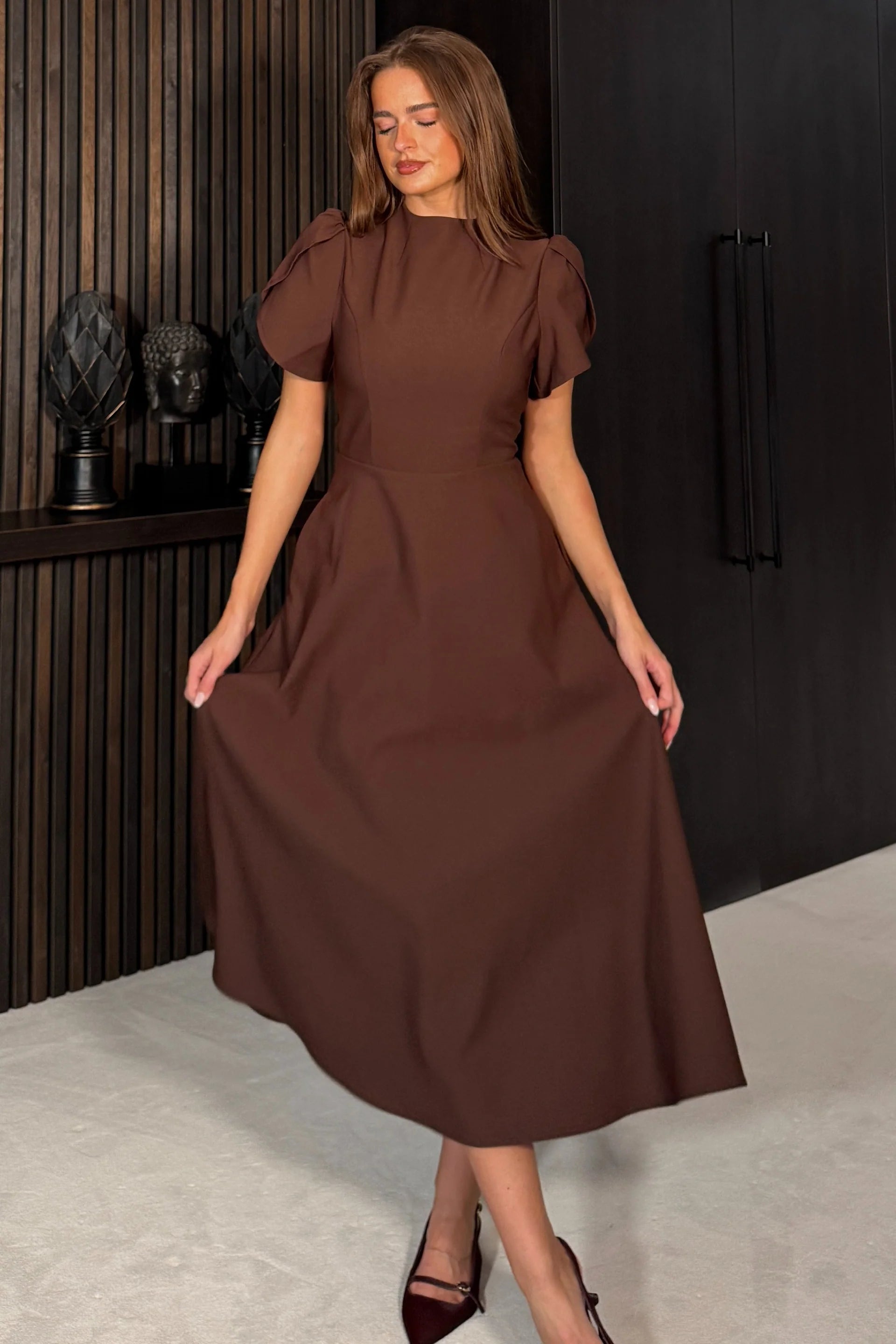 Woman wearing a brown dress in an indoor setting