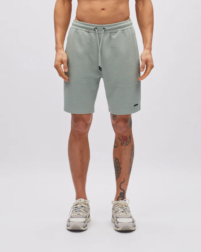 Person wearing light gray shorts on a white background