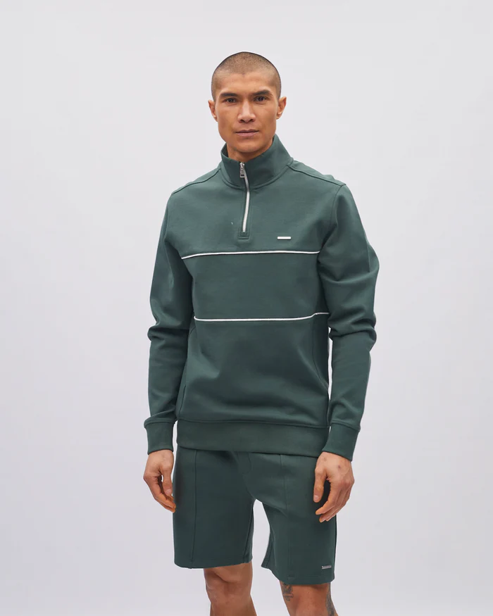 Man wearing a green tracksuit with a white stripe on a light gray background
