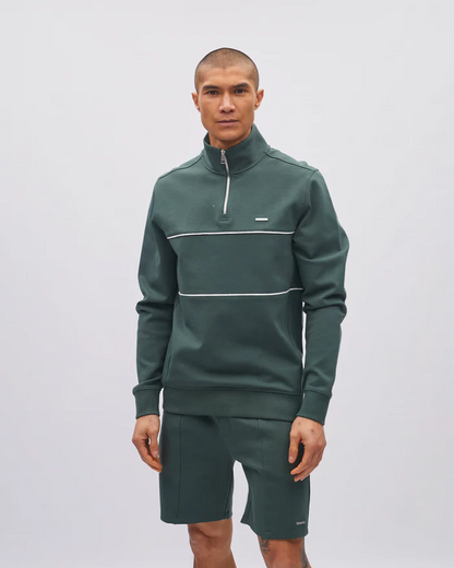 Man wearing a green tracksuit with a white stripe on a light gray background