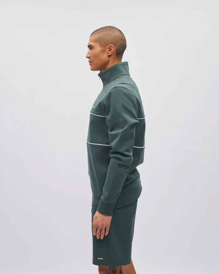 Person wearing a green tracksuit with white accents on a light gray background