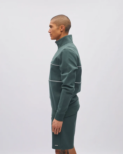 Person wearing a green tracksuit with white accents on a light gray background
