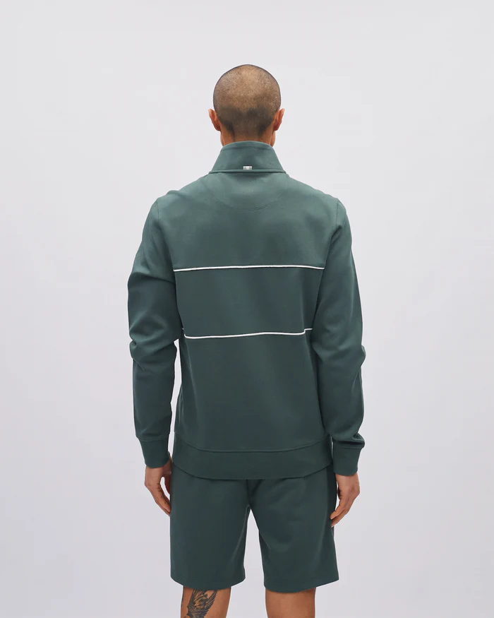 Person wearing a green tracksuit with white stripes on a light gray background