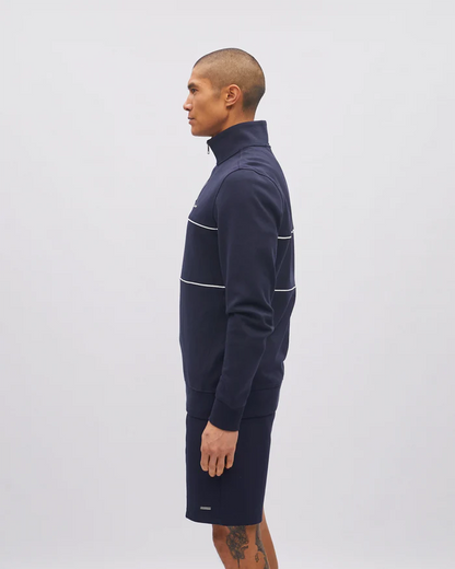 Man wearing a navy blue quarter-zip pullover with white accents on a light gray background