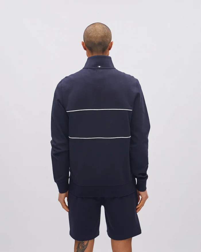 Man wearing a navy tracksuit with a white stripe on a light gray background