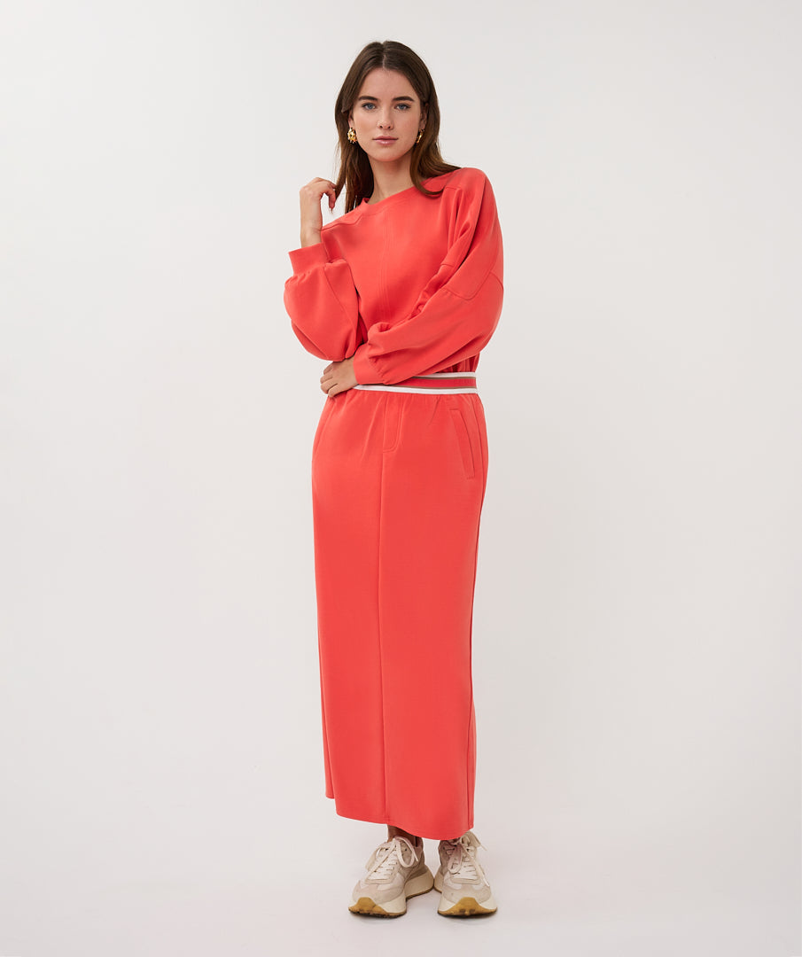 Woman wearing a coral outfit on a white background
