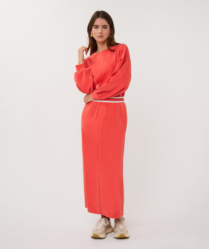 Woman wearing a coral outfit on a white background