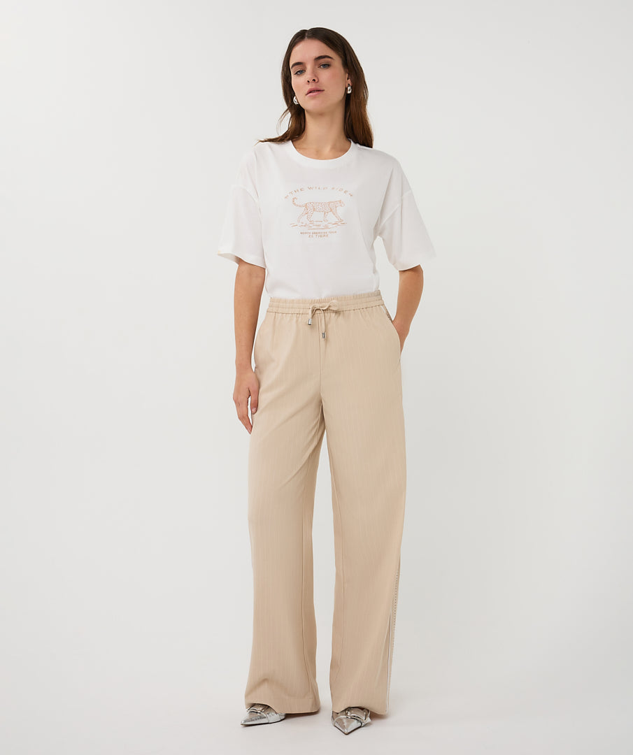 Woman wearing a white t-shirt and beige pants on a white background