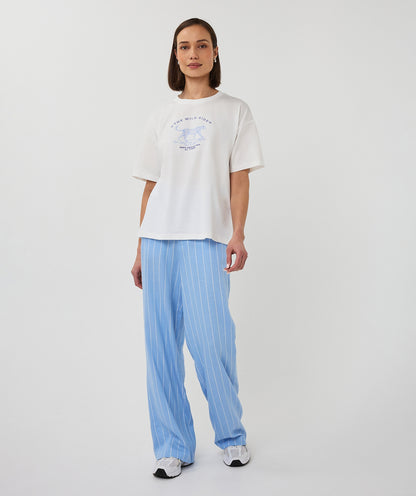 Person wearing a white t-shirt with a graphic design and light blue pants on a white background