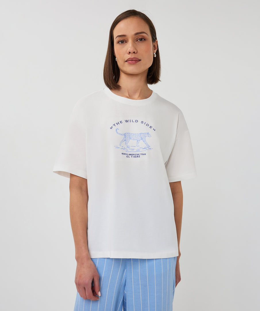 Person wearing a white t-shirt with a graphic design on a plain background