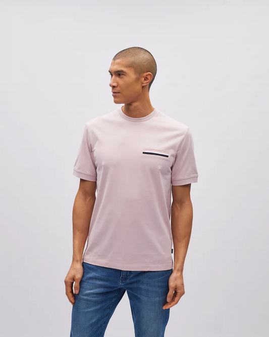 Man wearing a light pink t-shirt with a small black pocket detail on a plain background
