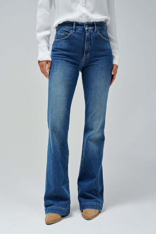 Person wearing blue flared jeans and a white shirt on a plain background