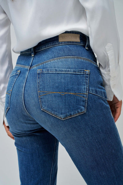 Person wearing blue jeans and a white shirt on a plain background