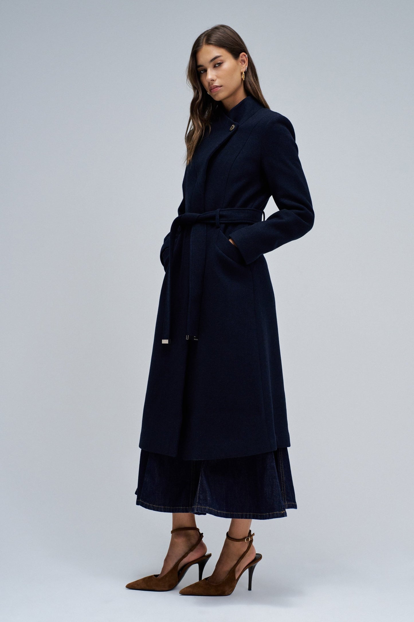 Woman wearing a navy blue coat on a light gray background