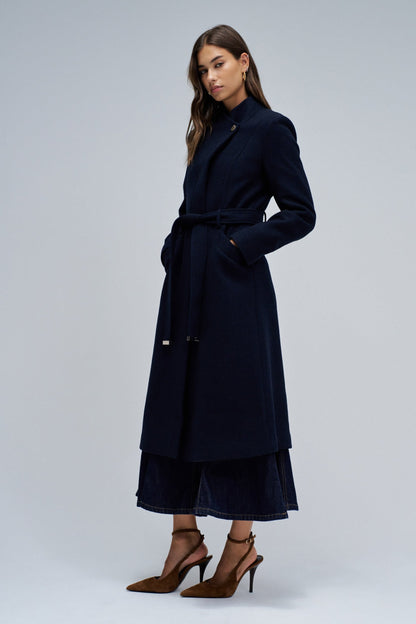 Woman wearing a navy blue coat on a light gray background