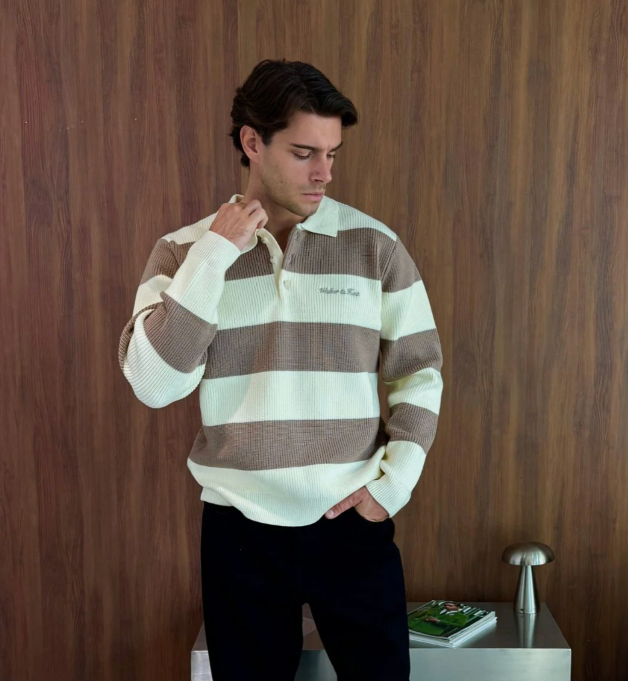 Man wearing a brown and white striped sweater against a wooden wall.