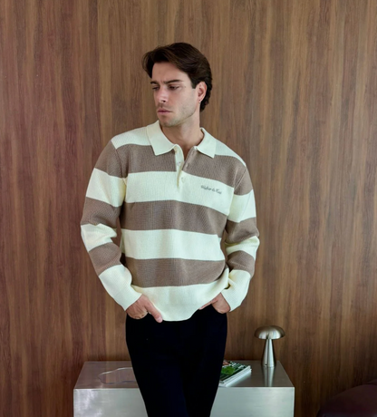 Man wearing a brown and white striped sweater against a wooden wall.