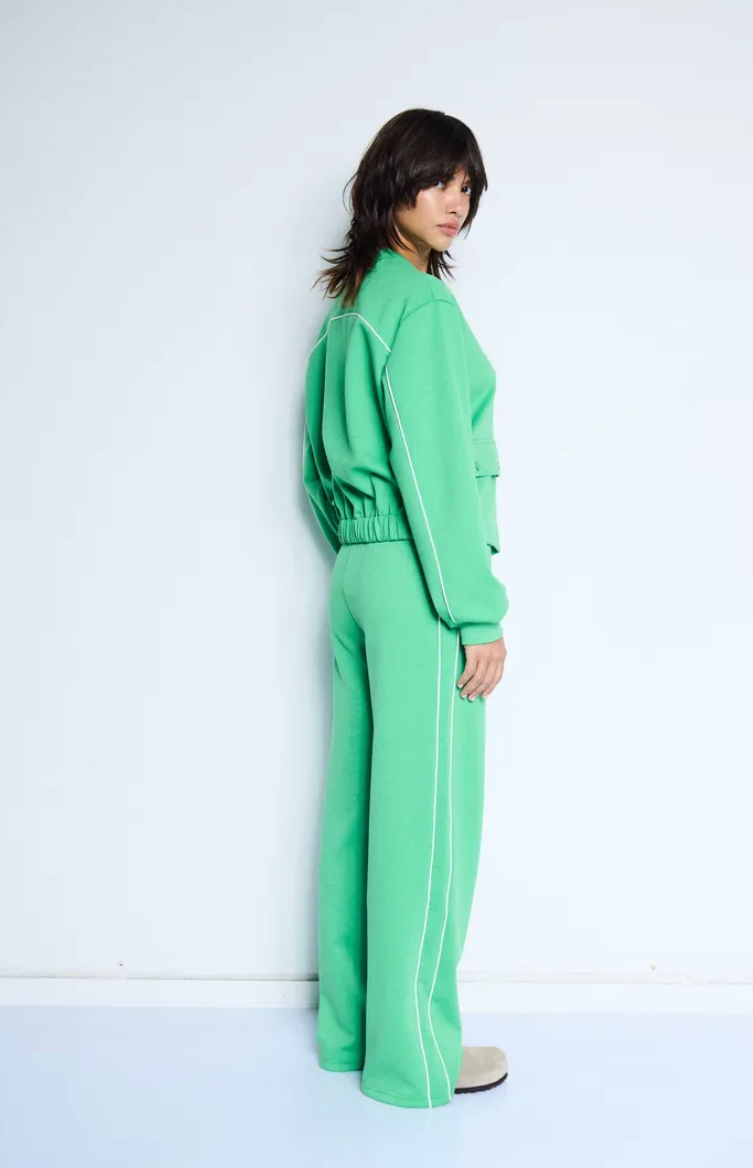 Person wearing a green outfit standing against a white background