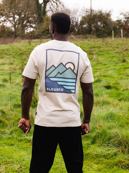 Person wearing a white t-shirt with a mountain graphic and 'BLEUARD' branding in an outdoor setting.