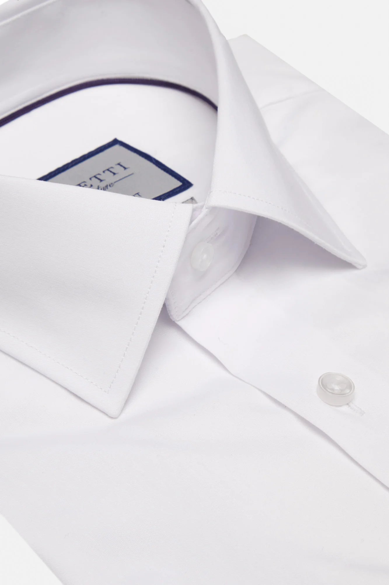 Close-up of a white dress shirt with a collar and button, featuring a brand label.